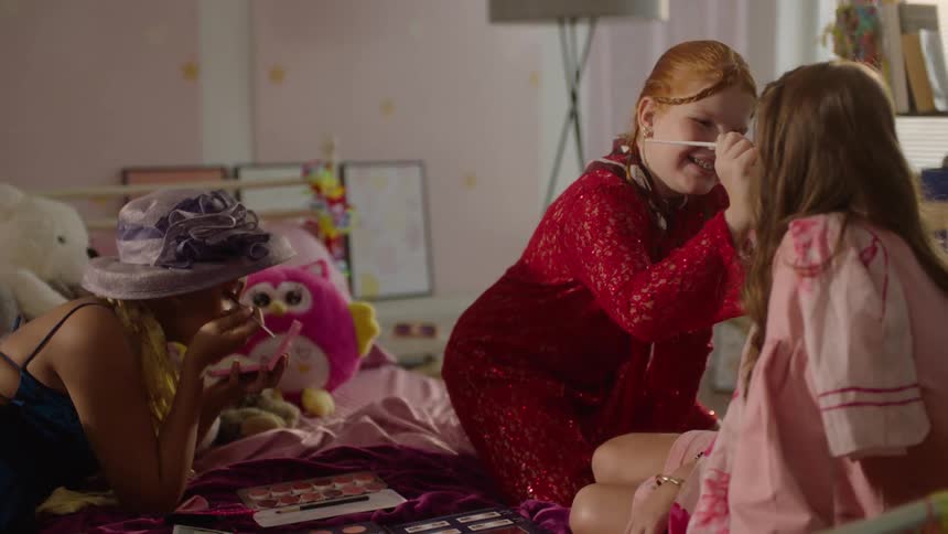 Girls apply makeup while playing dress up at home