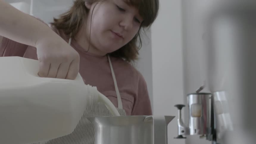 A woman pours milk into a vat