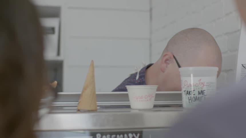 An ice cream worker serves two customers
