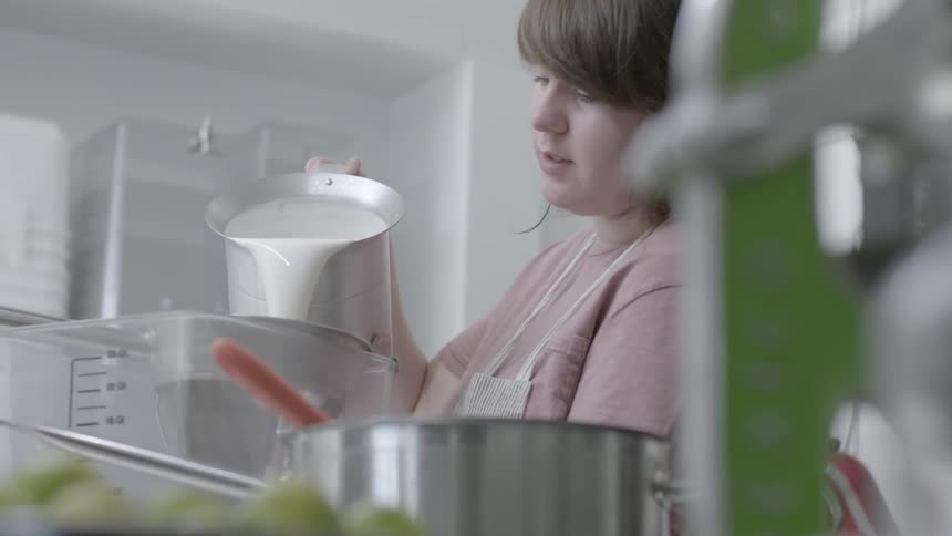 A woman pours a mixture into a vat