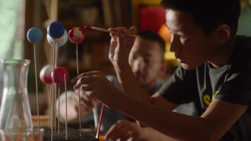 Father and son painting styrofoam balls on a model
