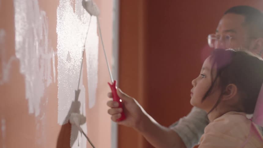 A father and daughter are painting the wall together