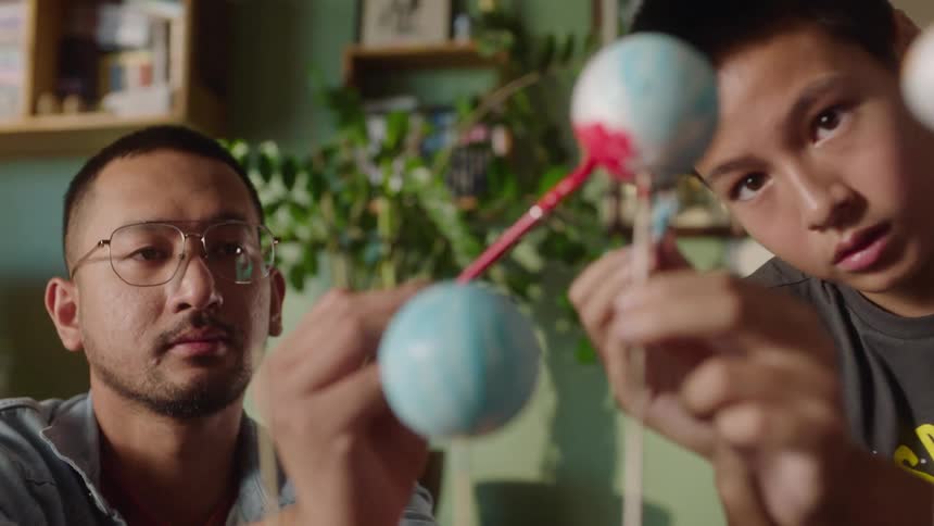 Man and boy paint planet models in a school project