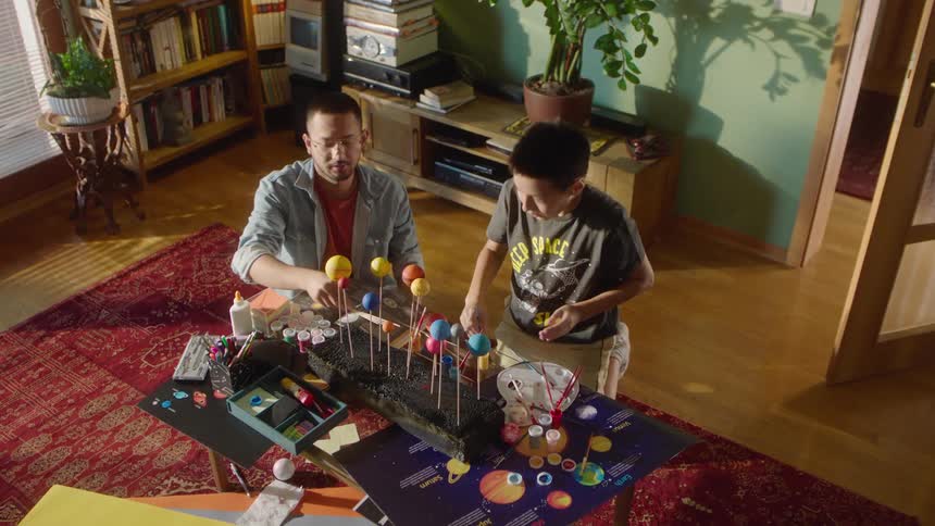 Father and son working on a model with colored balls in a school project