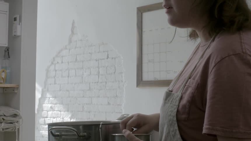 A woman is putting some spices in a bowl