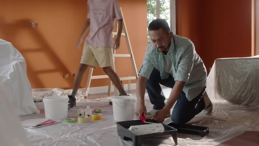 A father and son are painting the room together