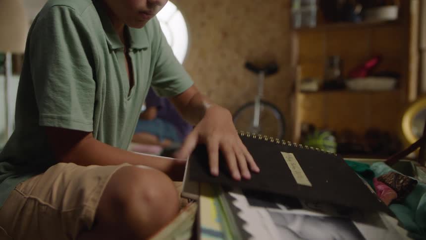 Two boys explore a suitcase of old memories in the attic
