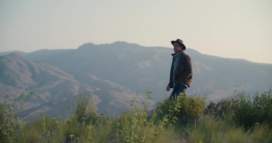 Man in hat walking one morning through the mountains
