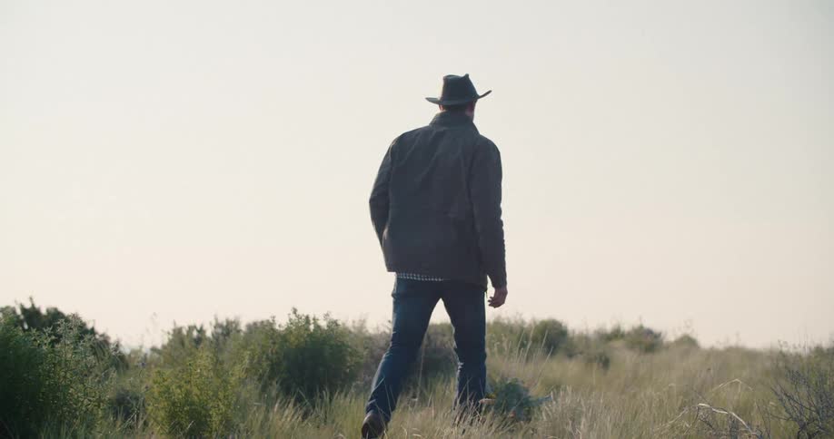 Man in hat and jeans walking on a mountain