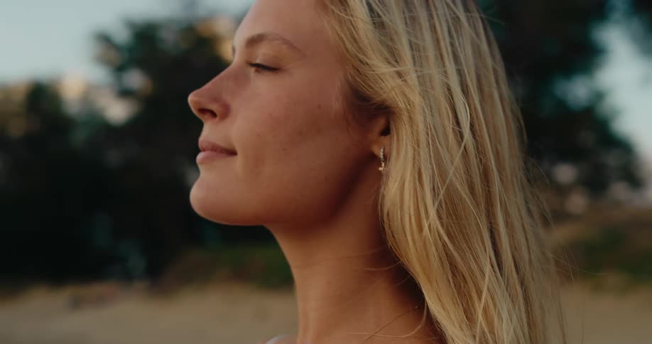 A camera is zoomed in on a womans face in profile as she looks forward and then closes her eyes