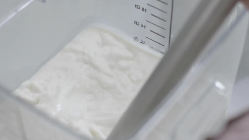 A person pours ingredients into a large measuring container