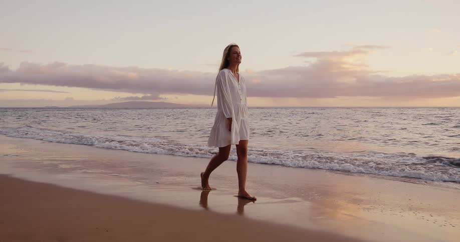 Woman in white beach coverup walking on the beach