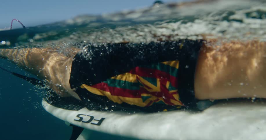 The man swims on the surfboard in the ocean