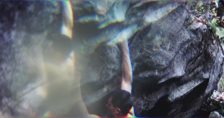 A muscular climber scales a rock wall distorted by motion