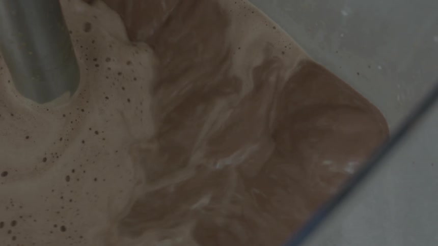 Chocolate liquid froths and then is churned in a vat