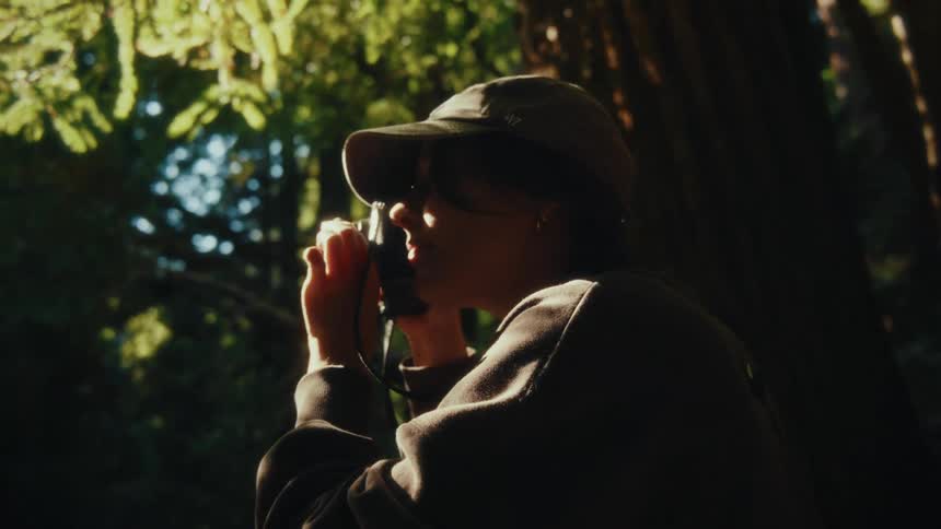 Female photographer takes a picture while standing in a forest on an autumn day