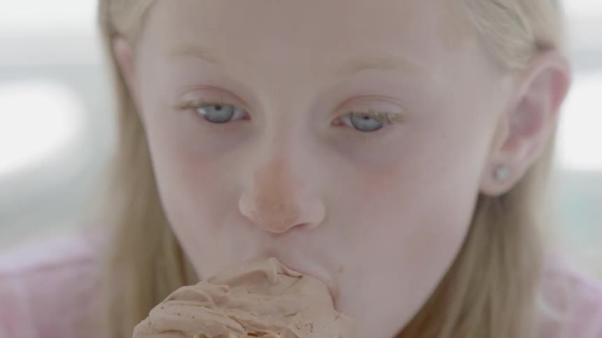 A young girl eats chocolate ice cream