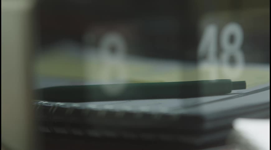 Green pen rests on a notebook next to a calendar