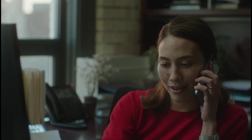 Woman in red talks on the phone at her desk