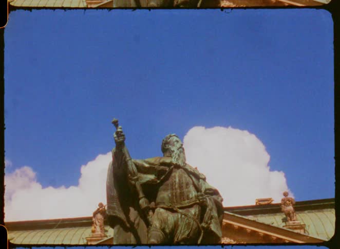 Bronze statue against a blue sky with clouds
