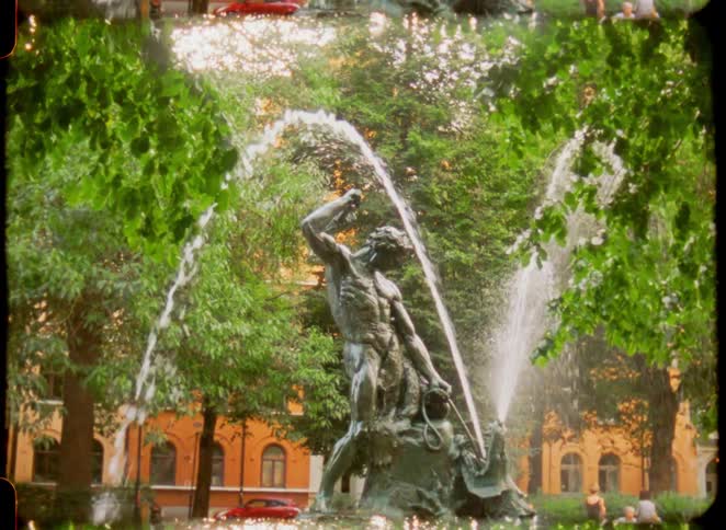 Bronze statue in a fountain with water jets in a treefilled park