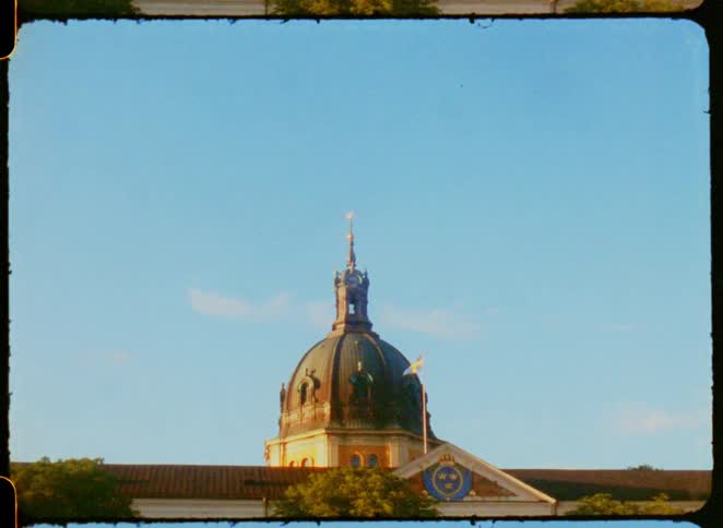 Dome of a historic building with the swedish flag against the blue sky
