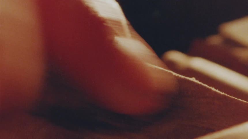 A close up of the hands of a carpenter sanding a small hole on a piece of wood