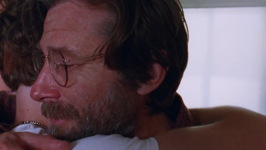 Bearded man with glasses hugs a young man emotionally