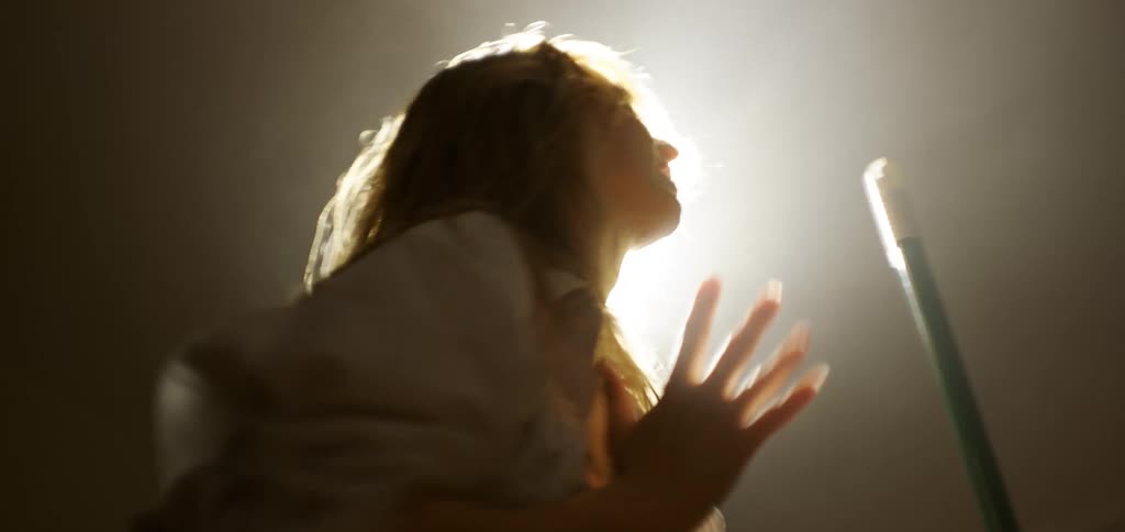 The woman is dancing and singing under a spotlight