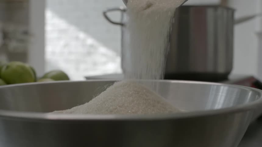 A person pours sugar into a silver bowl