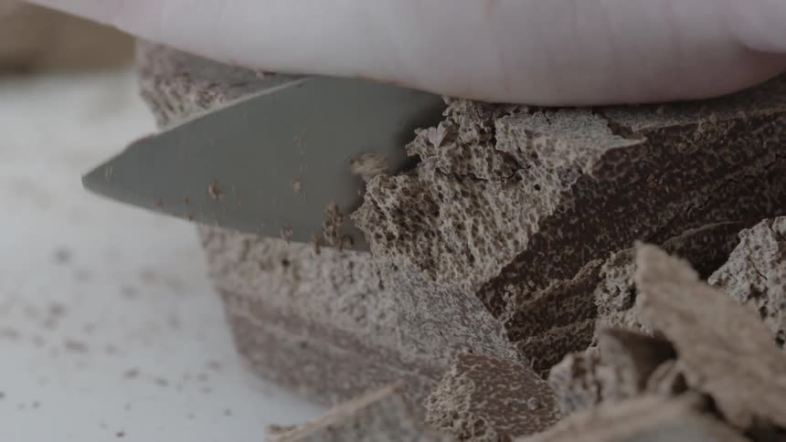 A large chocolate block is being cut up