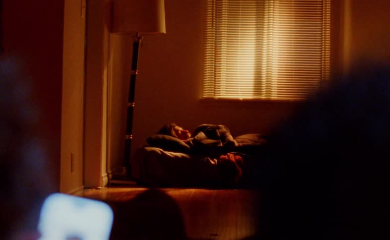 Two people in the foreground and another person in the background lying in a room