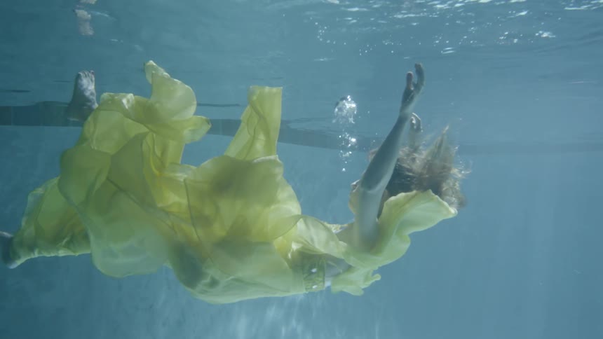 A woman in a yellow dress falls under the water