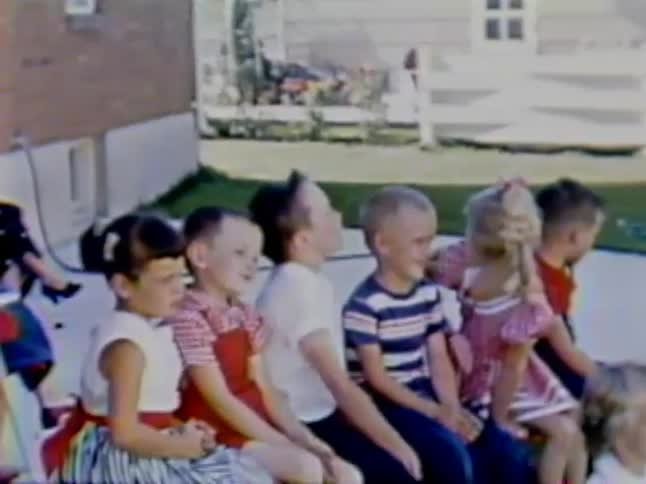 Boys and girls sit in a row outside