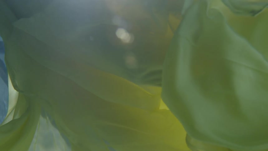 A long yellow dress floats in the water
