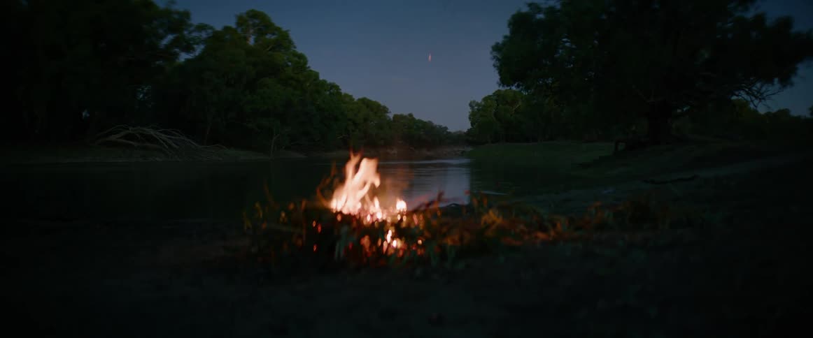 Campfire burning by the riverside at dusk