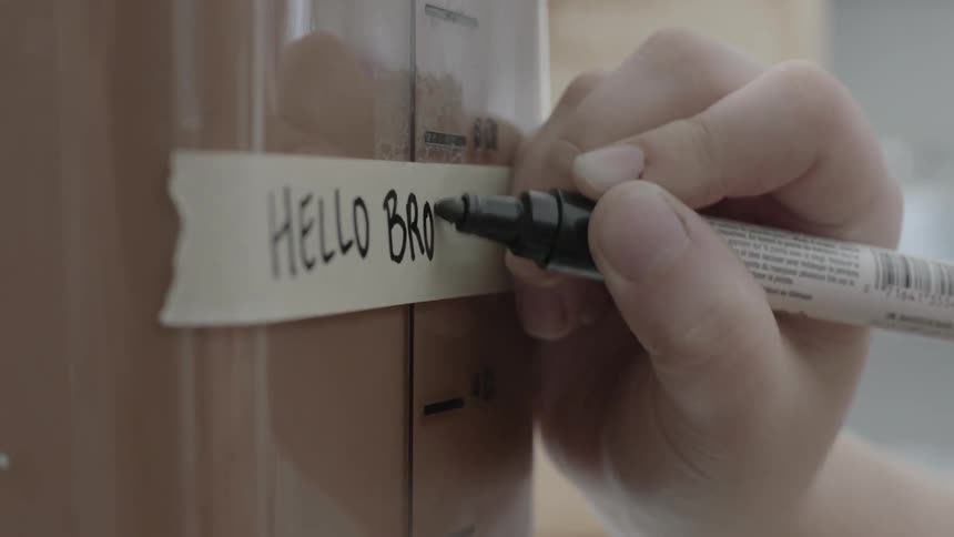 A man writes with a marker labeling a container