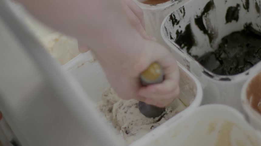 Hand scoops ice cream out of a bucket