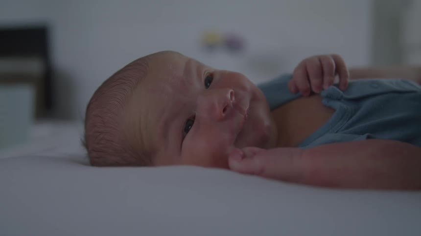 Baby lying on a white mattress wearing blue clothing