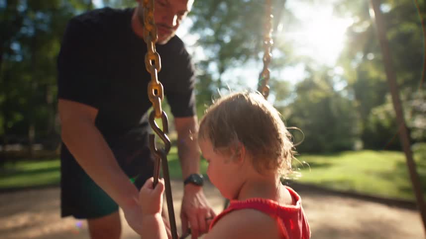 A man pushes a child on a swing