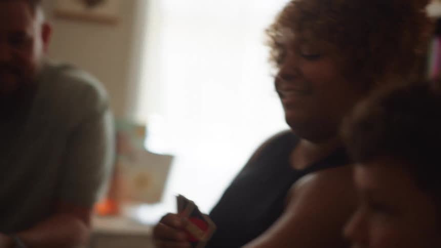 A family is playing a game playing cards at home