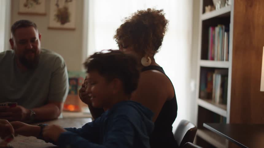 Four people sitting at a table having fun playing cards