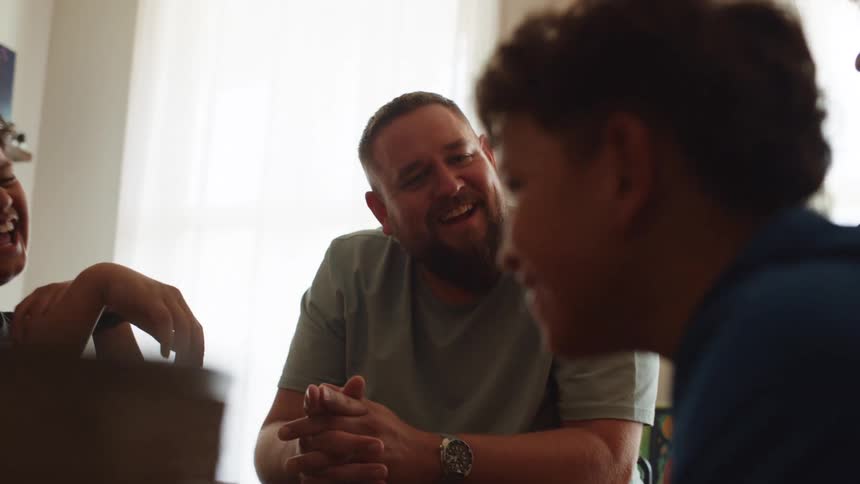 Four people including two adults and two children sitting at the table talking