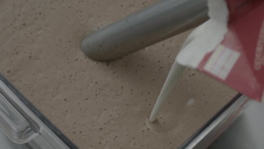 A person pours milk into ice cream mixture