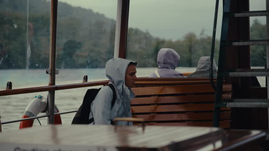 A person sits inside a boat looking out at the water