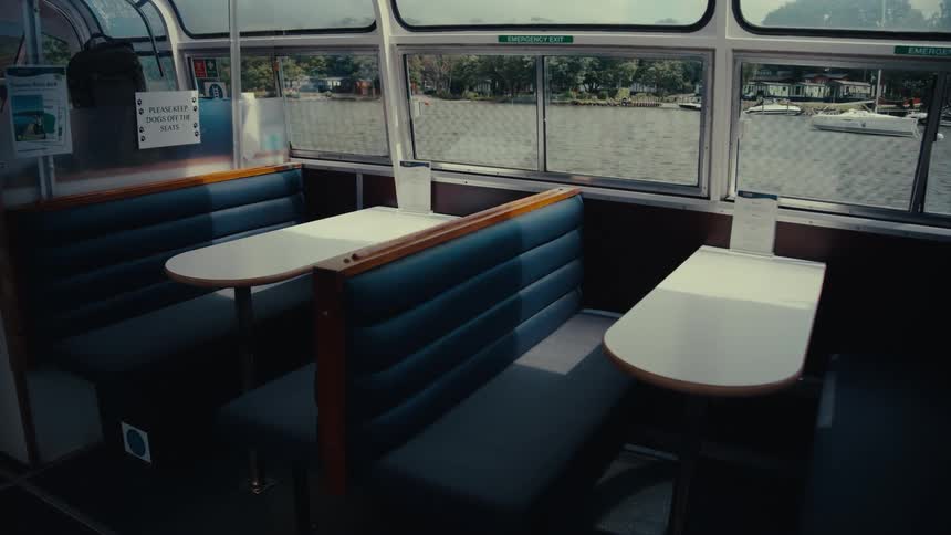 Empty booth seating inside a boat overlooks the river