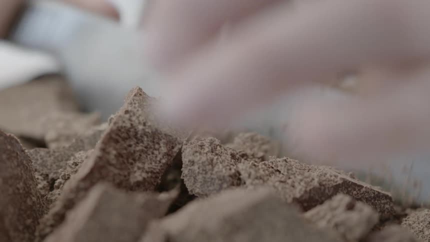 A person is chopping up chocolate with a knife