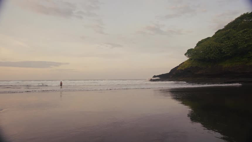 The man stands in the tide on the beach