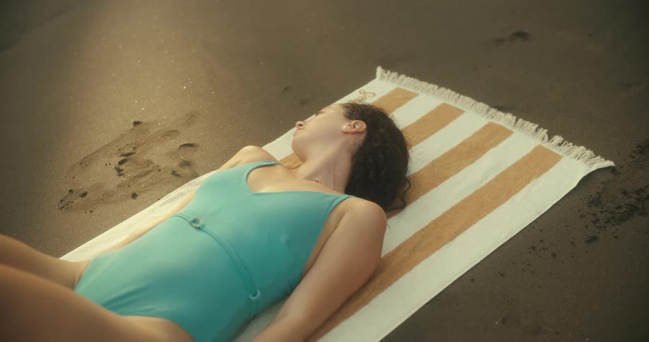 Woman lies on a towel on the beach to sunbathe