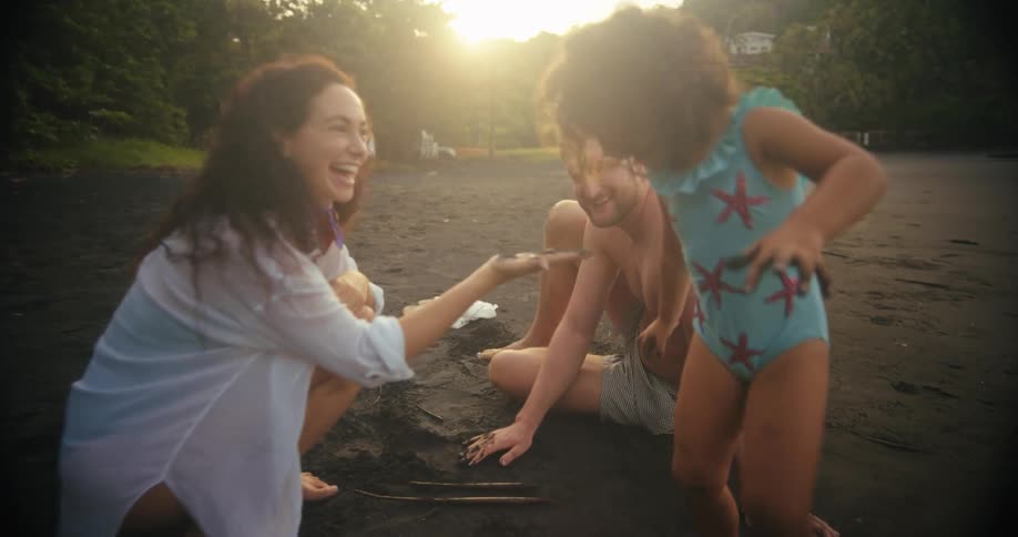 A family enjoys playful time together on a sandy beach at sunset